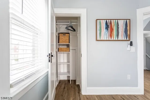 a view of a hallway with wooden floor and a bathroom