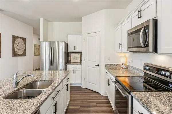 a large kitchen with stainless steel appliances granite countertop a lot of counter space and wooden floor
