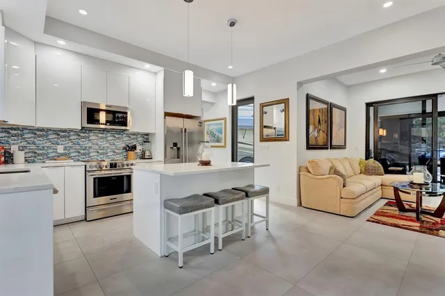 a kitchen with stainless steel appliances granite countertop a stove top oven a sink dishwasher a dining table and chairs with wooden floor