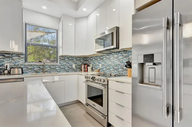 a kitchen with stainless steel appliances granite countertop a refrigerator and a sink