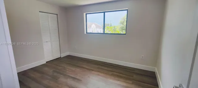 an empty room with a window and a wooden floor