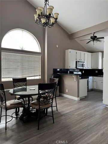 a kitchen with stainless steel appliances kitchen island granite countertop a table chairs sink and cabinets