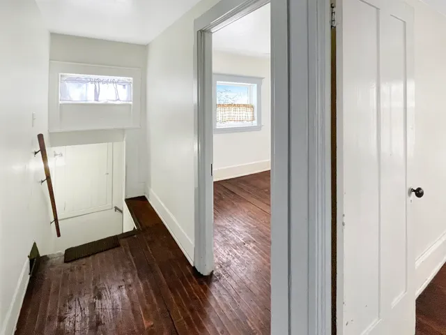 a view of a hallway with wooden floor and staircase
