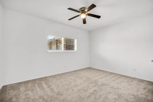 an empty room with a window and a fan