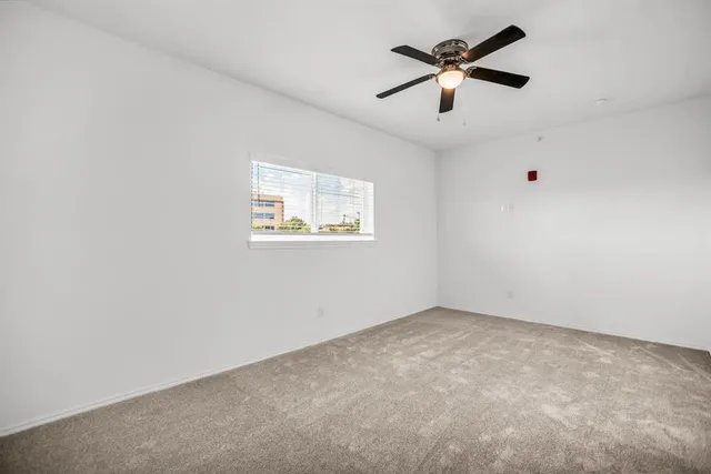 an empty room with ceiling fan and window