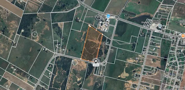 a view of dirt field with trees in the background