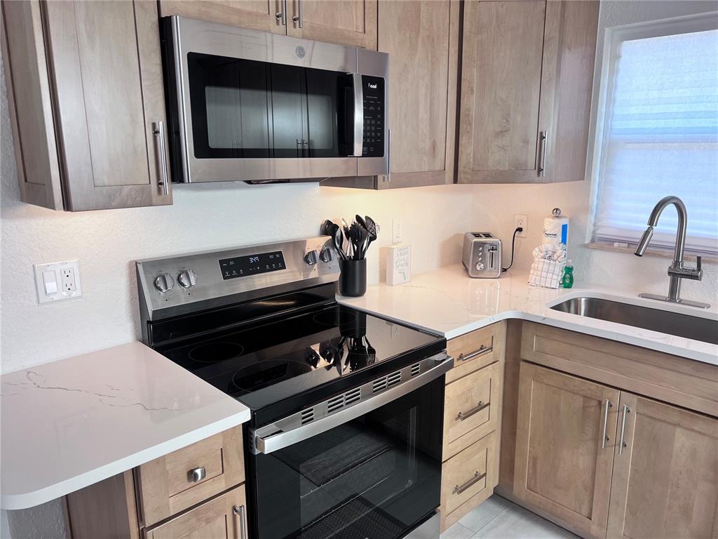6154 Midnight Pass Road, Unit B06 Sarasota, FL 34242 - Photo 4 of 18 a kitchen with microwave cabinets and stove top oven