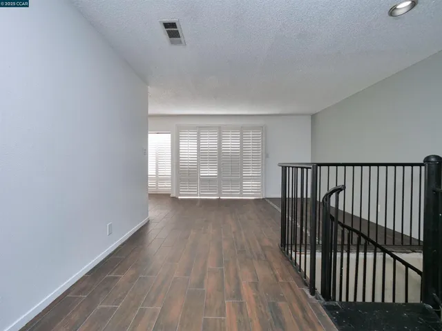 a view of empty room with wooden floor and fireplace