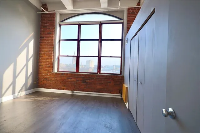 a view of an empty room with wooden floor and windows
