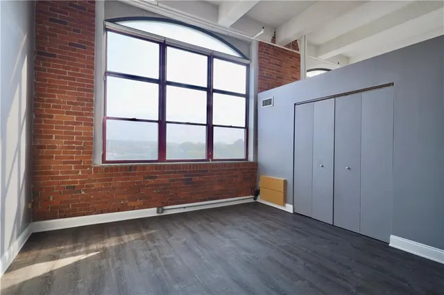 a view of an empty room with wooden floor and window