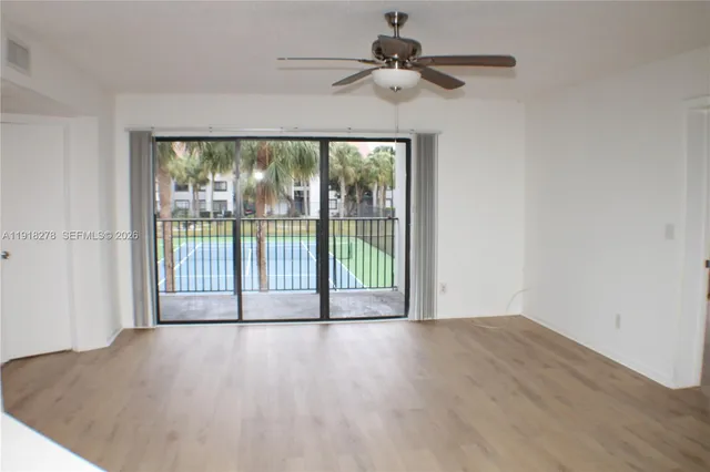 a view of a room with wooden floor and a ceiling fan
