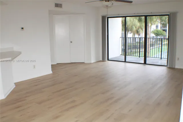 a view of a big room with wooden floor and windows