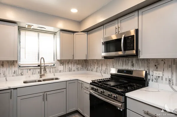 a kitchen with stainless steel appliances a sink a stove cabinets and a window