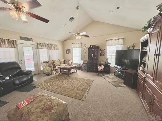 a living room with furniture a flat screen tv and a refrigerator