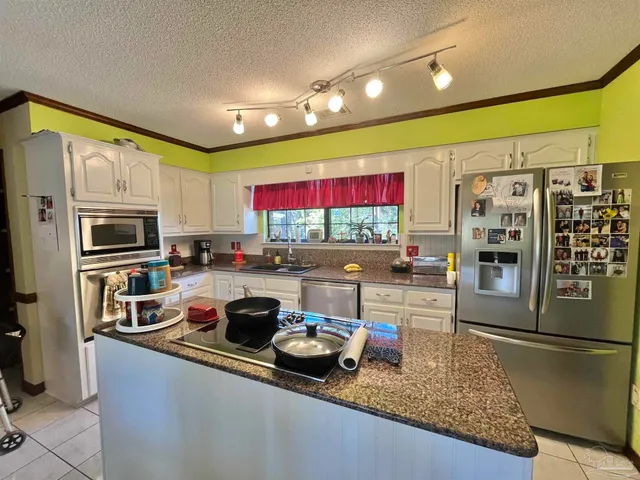 a kitchen with stainless steel appliances granite countertop a refrigerator sink stove and cabinets