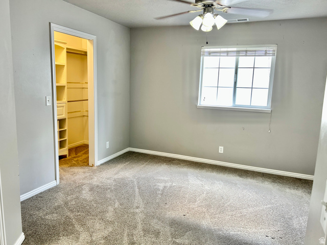 672 West 720 South Logan, UT 84321 - Photo 6 of 15 Neutral-toned room featuring a walk-in closet with built-in shelving, a ceiling fan with light fixture, and a window with horizontal blinds