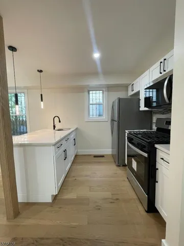 a large white kitchen with stainless steel appliances granite countertop a stove and a sink