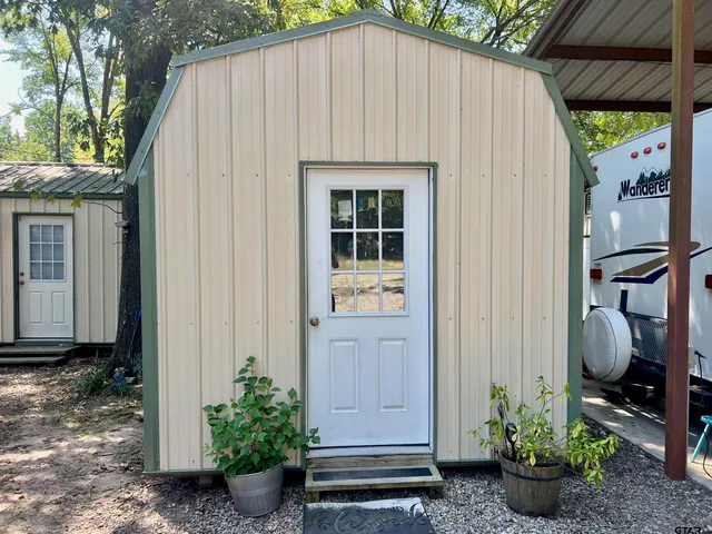 a view of a small house with potted plants next to a yard