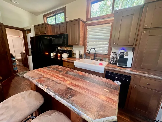 a kitchen with stainless steel appliances kitchen island granite countertop a refrigerator a stove a sink dishwasher and wooden cabinets with wooden floor