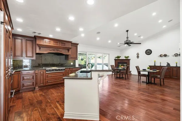 a kitchen with stainless steel appliances a stove a sink a oven a dining table and chairs with wooden floor