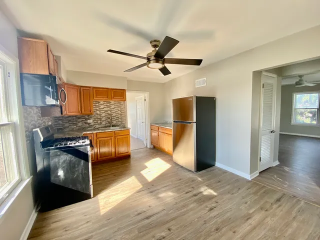 a kitchen with stainless steel appliances granite countertop a refrigerator a stove and a wooden floors