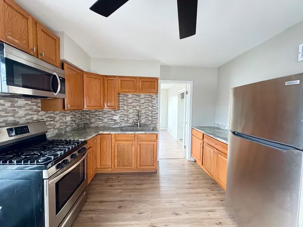 a kitchen with stainless steel appliances granite countertop a refrigerator a stove a sink and a microwave