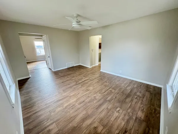 an empty room with wooden floor and windows