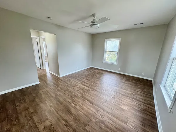 an empty room with wooden floor and windows
