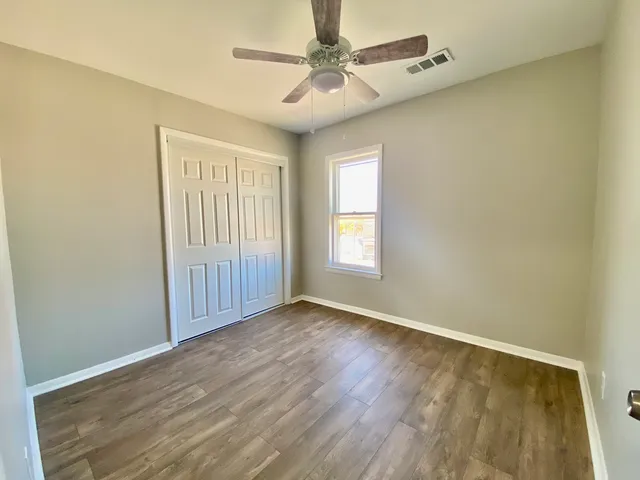 an empty room with windows and fan