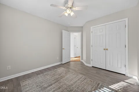 a view of empty room with wooden floor and fan