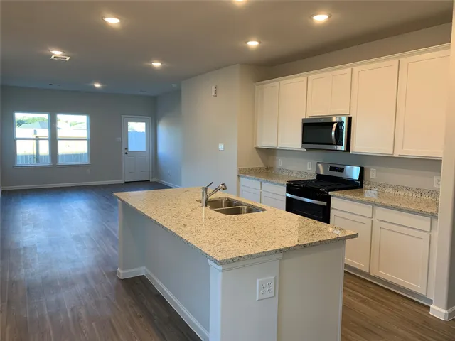 a kitchen with kitchen island a sink dishwasher stove and microwave with wooden floor