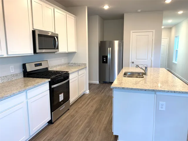 a kitchen with granite countertop a sink stove and refrigerator
