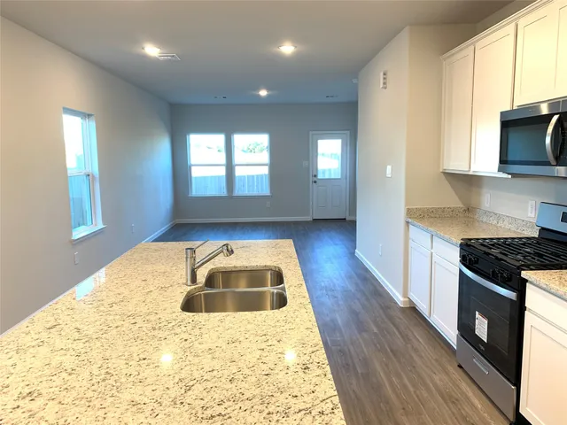 a kitchen with granite countertop a stove a sink and a microwave