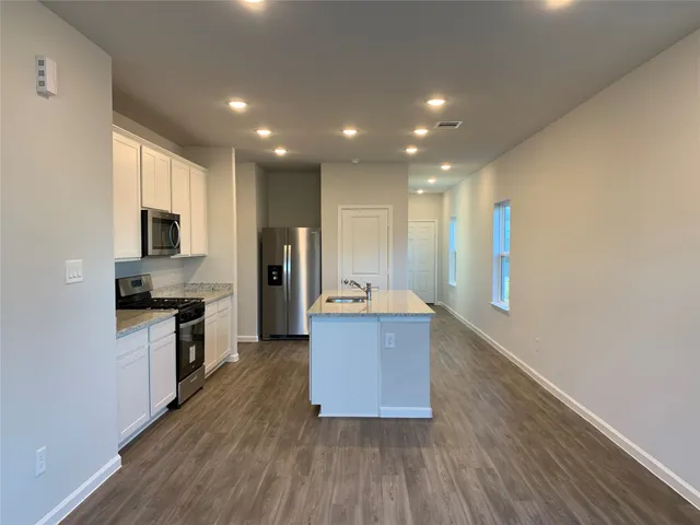 a large kitchen with stainless steel appliances granite countertop a large counter top a stove and a wooden floors