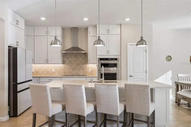 a kitchen with stainless steel appliances granite countertop a table chairs stove and refrigerator