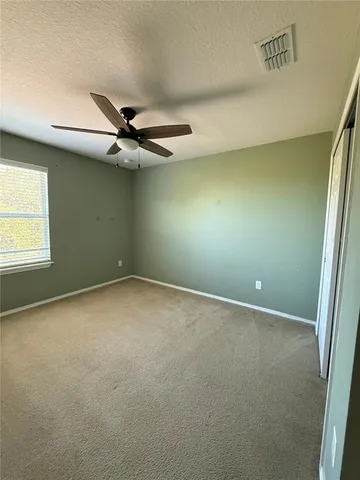 an empty room with a ceiling fan and carpet