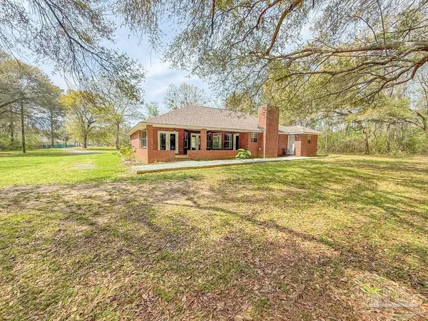 a view of a big house with a big yard and large trees