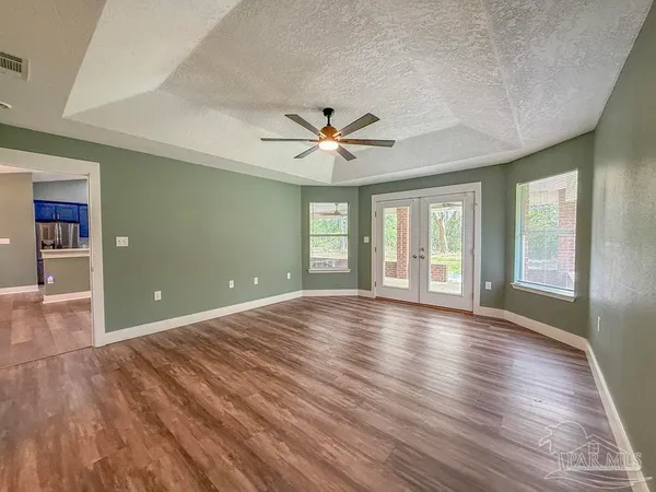 a view of an empty room with window and wooden floor