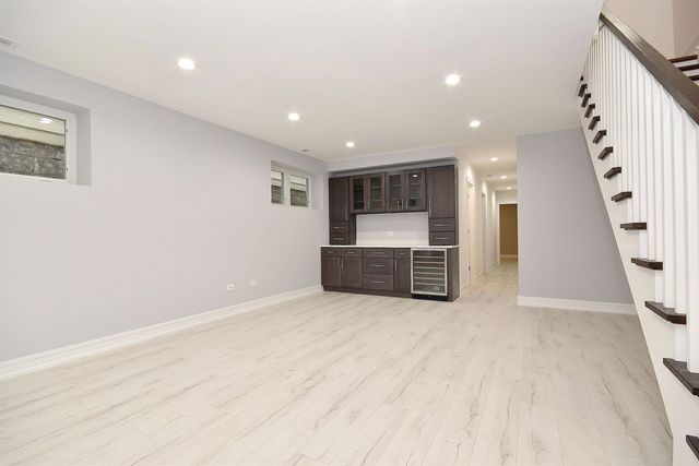 an empty room with wooden floor chandelier and windows