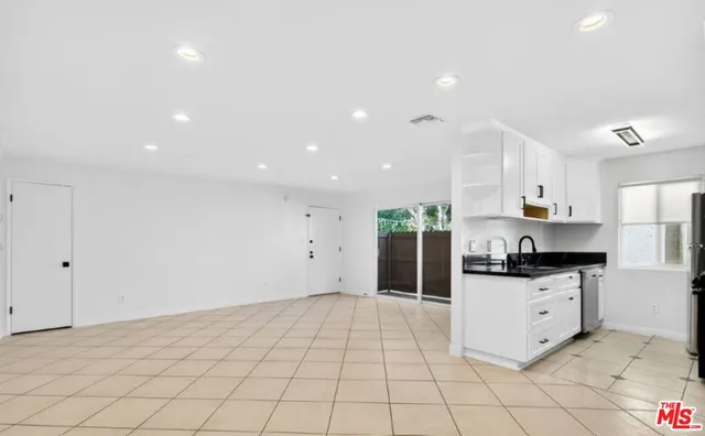 a kitchen with granite countertop a sink and white cabinets