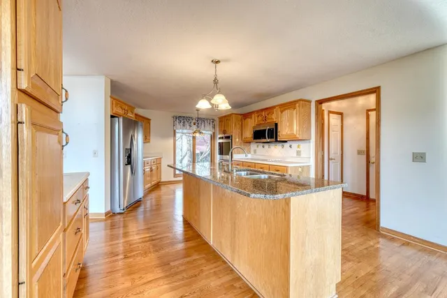 a large kitchen with kitchen island granite countertop a sink and cabinets