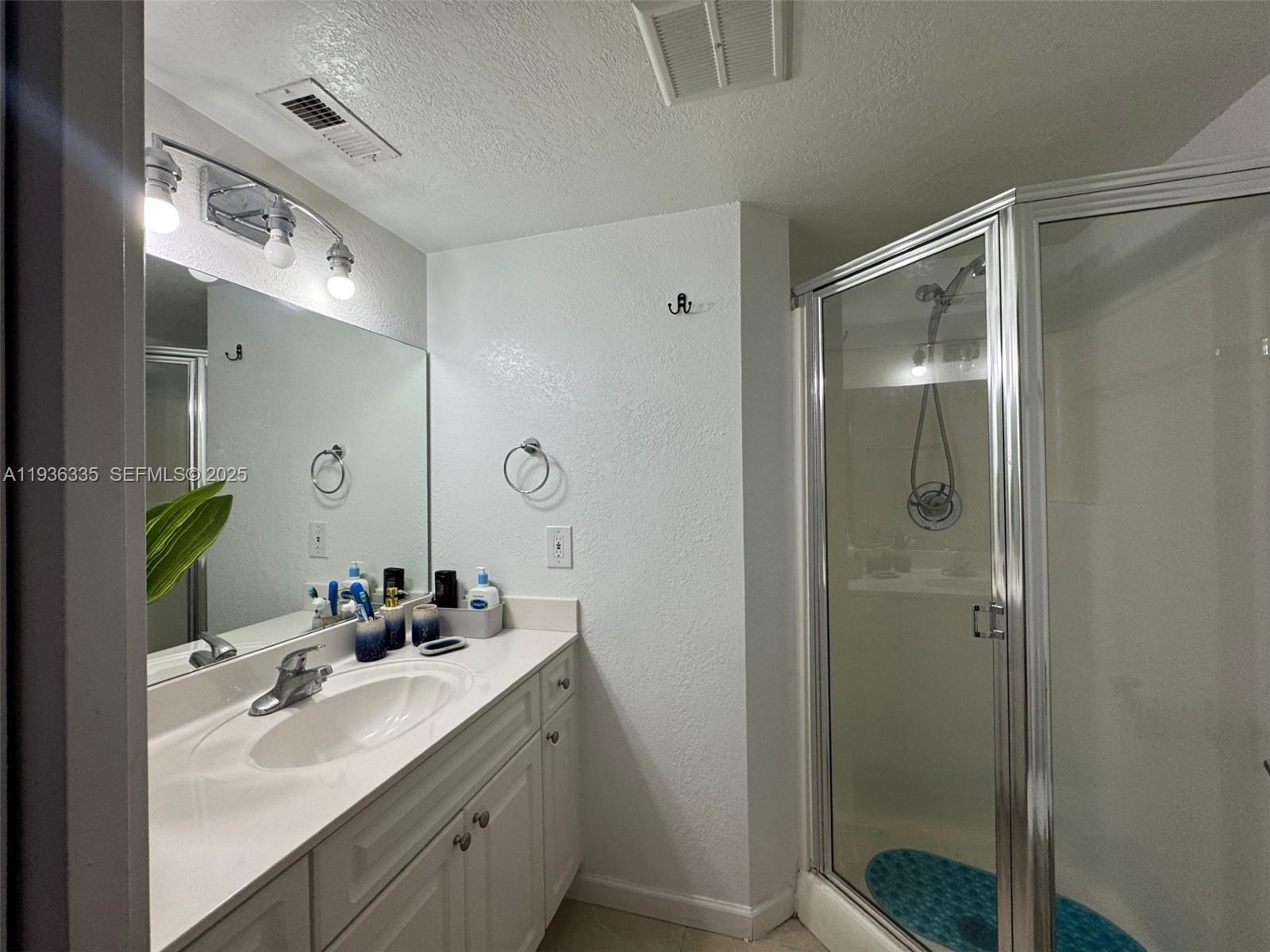 8116 Severn Drive, Unit C Boca Raton, FL 33433 - Photo 19 of 19 a bathroom with a double vanity sink mirror and shower