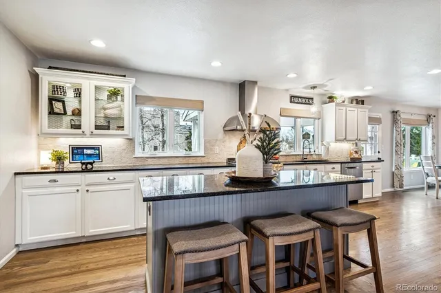 a kitchen with kitchen island granite countertop a table chairs sink and wooden cabinets