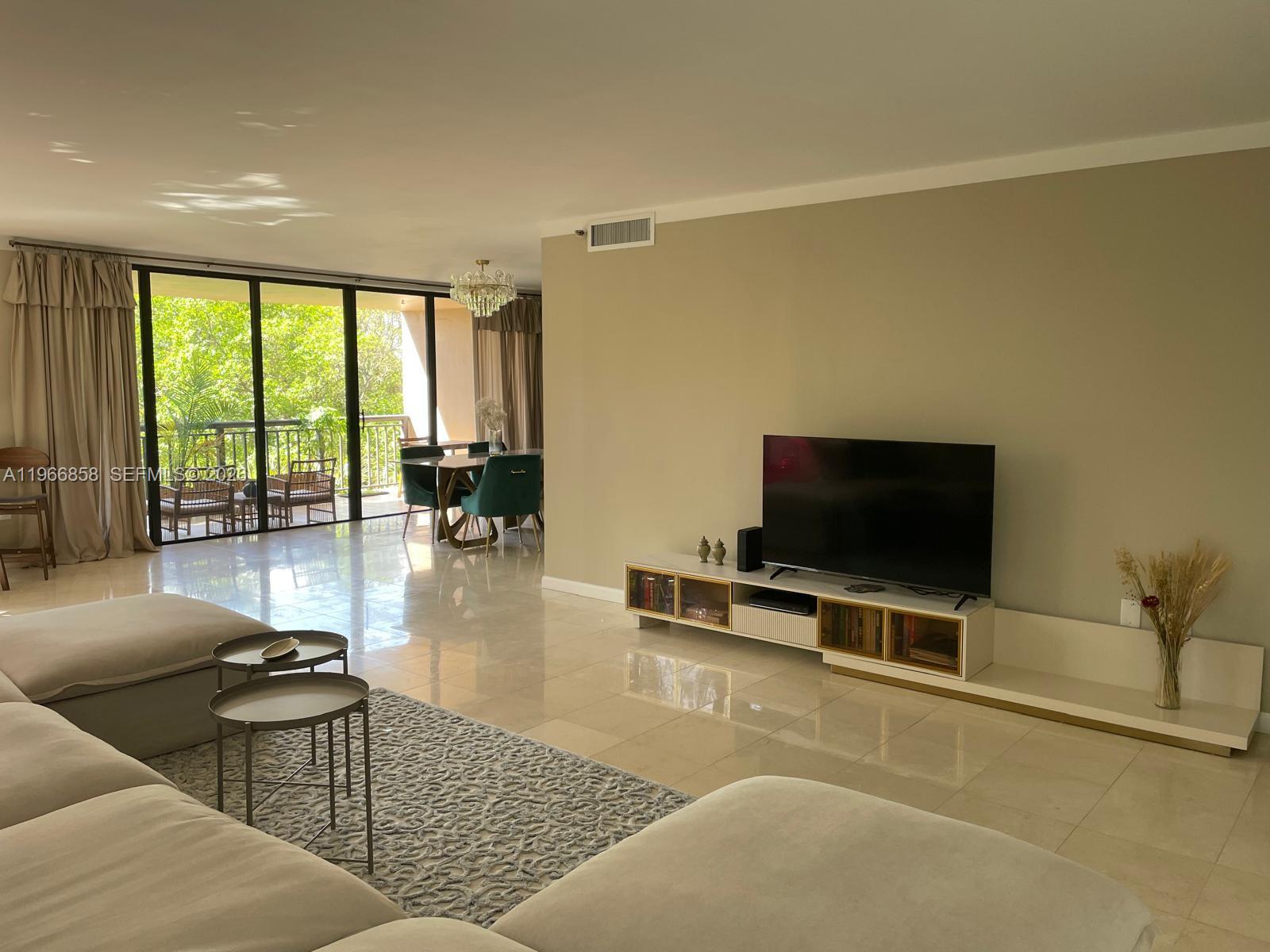 10175 Collins Avenue, Unit 208 Bal Harbour, FL 33154 - Photo 2 of 16 a living room with furniture and a flat screen tv