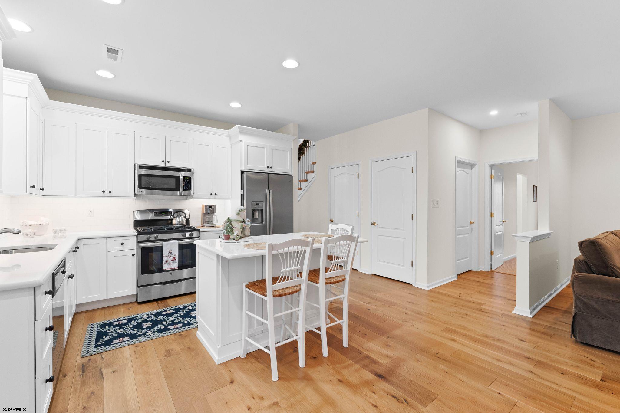 11 Daffodil Road Egg Harbor Township, NJ 08234 - Photo 13 of 50 a kitchen with stainless steel appliances granite countertop a stove top oven a refrigerator a sink and a dining table with wooden floor