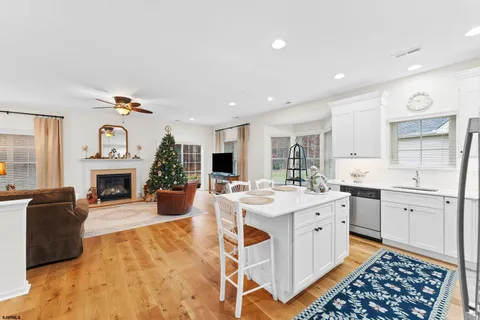 a large white kitchen with a stove a sink dishwasher and a fireplace with wooden floor