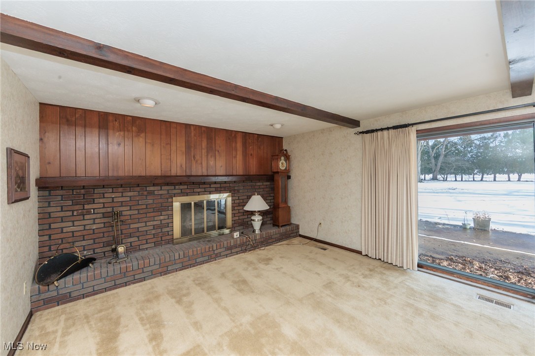 4127 Huffman Road Medina, OH 44256 - Photo 20 of 49 Unfurnished living room with beam ceiling, a fireplace, carpet, wooden walls, and wallpapered walls