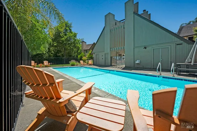a view of pool with lawn chairs and plants