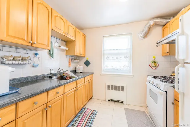 a kitchen with granite countertop a sink a stove a refrigerator and cabinets