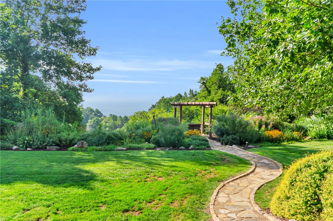 116 Witch Hazel Trail Landrum, SC 29356 - Photo 25 of 26 A tranquil garden path leads to a picturesque pergola, offering serene views of the surrounding landscape.